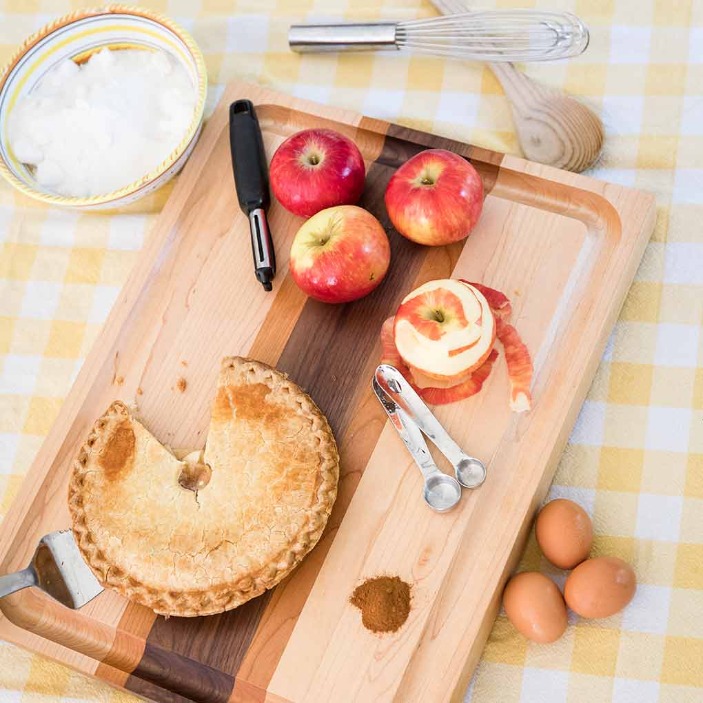 apples-dessert Apples peeled and an apple tart on a striped designer cutting board