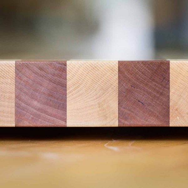 End grain detail of a striped wooden cutting board consisting of two different colored woods together